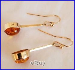 An antique pair of 9ct Yellow gold drop earrings. Set with oval Baltic Amber
